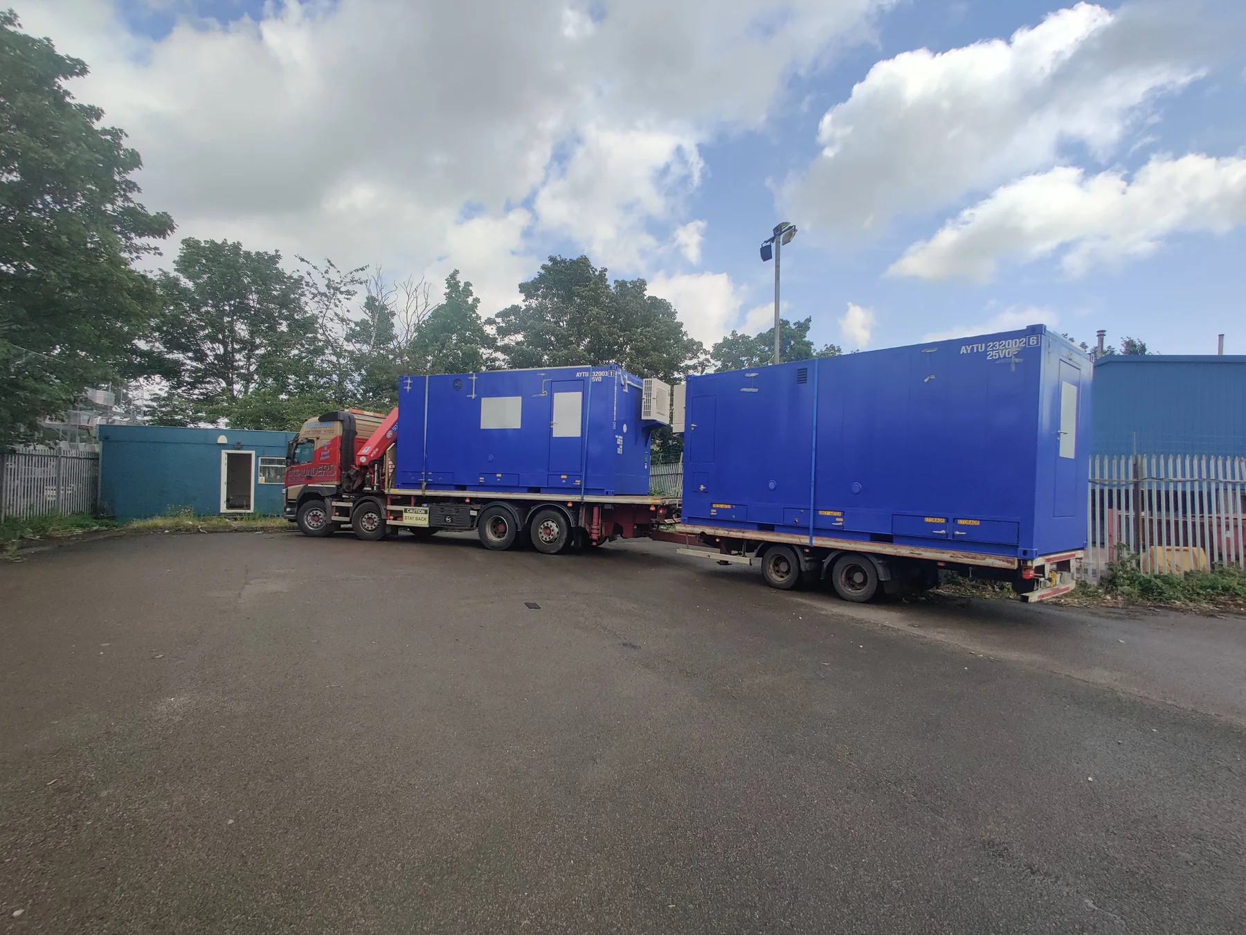 Delivery vehicles positioned for unloading modular REEF kitchens